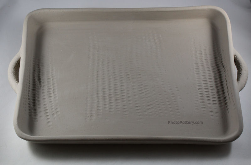 Sample pottery serving tray made on plaster drape mold. Textured handles added. Stoneware in greenware state.