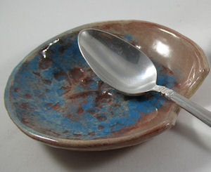 Sample spoon rest made on small round plaster mold, shown here with teaspoon; Earthenware slab with texture.